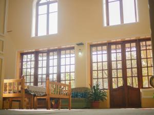 a room with large windows and a table and benches at Guest House Ikathouse in Margilan