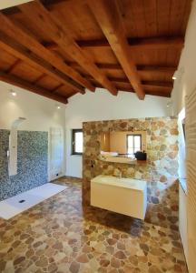 Agriturismo Borgo Biaia في Camporgiano: حمام بحائط حجري وحوض استحمام كبير