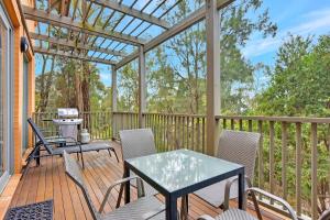 a deck with a table and chairs and a pergola at Villa Executive 2br Cypress DS located within Cypress Lakes Resort in Pokolbin