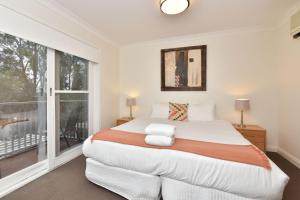 een slaapkamer met een groot bed en een raam bij Villa Executive 2br Cypress DS located within Cypress Lakes Resort in Pokolbin