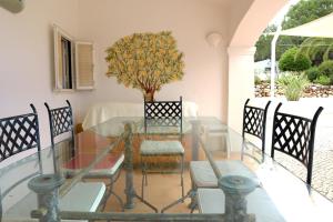 Villa Quintinha في Mexilhoeira Grande: غرفة طعام مع طاولة وكراسي زجاجية