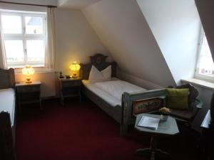 a small bedroom with a bed and two windows at Hotel Haus Appelberg in Dinkelsbühl