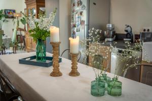 a table with candles and flowers in vases on it at Le Petit Matin in Bayeux