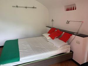 un letto con cuscini rossi e bianchi e una lampada di Medieval mountain setting with private garden a Colletta
