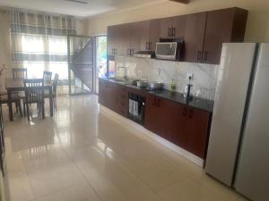 a kitchen with a refrigerator and a table with chairs at SABATH LODGE TWO in Cape Town