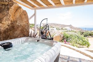 un patio con bañera de hidromasaje y vistas al océano en Dioni Villa Mykonos, en Paraga