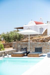 a swimming pool with two chairs and an umbrella at Dioni Villa Mykonos in Paraga