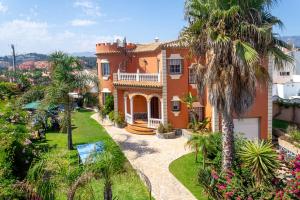 a large orange house with palm trees in front of it at Villa Mirador Faro by Villa Plus in Mijas Costa