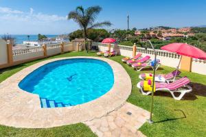 a swimming pool with chairs and umbrellas and the ocean at Villa Torreon Faro by Villa Plus in Mijas Costa
