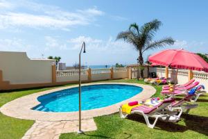 a swimming pool with two lawn chairs and an umbrella at Villa Torreon Faro by Villa Plus in Mijas Costa