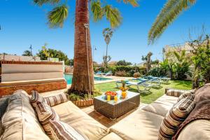 a backyard with a couch and palm trees and a pool at Villa La Cala Playa by Villa Plus in La Cala de Mijas