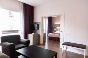 ein Wohnzimmer mit einer Couch und ein Zimmer mit einem Bett in der Unterkunft Hotel Serrano in Madrid