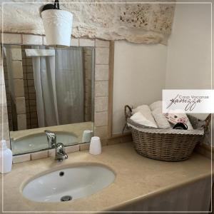bagno con lavandino e cesto di asciugamani di Trullo Eliana ad Alberobello