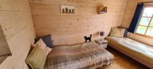 a bedroom with two beds and a black cat standing on the corner at Siedlisko Natura in Sułomino