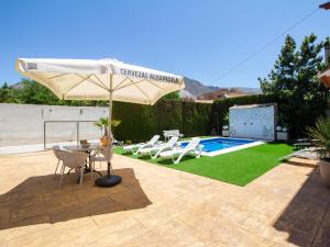 un patio con ombrellone e sedie e una piscina di Casa alegría a Dúrcal