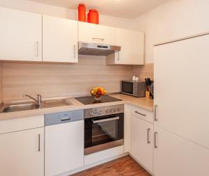 La cuisine est équipée de placards blancs, d'un évier et d'une cuisinière. dans l'établissement Appartement 204, à Bichlbach