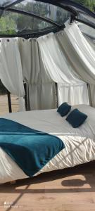 Cama blanca con almohadas azules bajo un dosel en Les Perles Catalanes en Vinça
