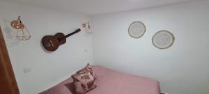 a bedroom with a guitar on a white wall at Casa da Andorinha in Pardieiros