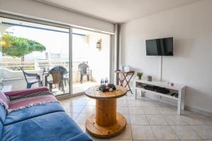 a living room with a blue couch and a table at Studio Daisy / charmant / Terrasse / lumineux / plage à 5 min in La Grande-Motte