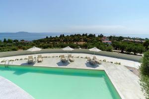 - une piscine avec des chaises et des parasols dans un complexe dans l'établissement Casa Bloo 360, Adults Only, à Kalogria