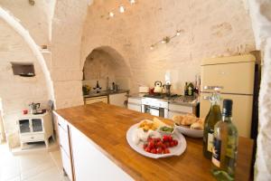 eine Küche mit einer Theke mit einem Teller Essen und Weinflaschen in der Unterkunft Villa Trulli Isabella by Villa Plus in Martina Franca