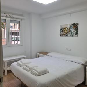 a white bedroom with two white towels on a bed at La Victoria 5 in Córdoba