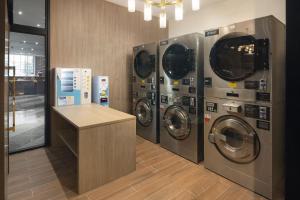 春武里的住宿－Hotel Nikko Amata City Chonburi，洗衣房配有3台洗衣机和1个柜台