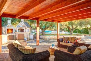 eine überdachte Terrasse mit Stühlen, einem Sofa und einem Kamin in der Unterkunft Villa Trulli Carolina by Villa Plus in Noci