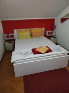 a bedroom with a white bed with a red wall at Hotel Asikot in Gevgelija