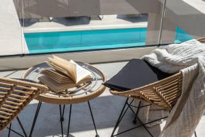 a glass table with a book on it next to two chairs at Delight Luxury Villa in Zakynthos Town