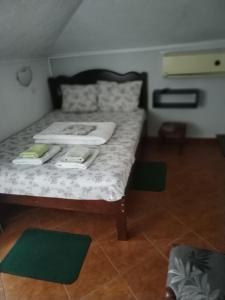 a bed in a room with green mats on the floor at Hotel Asikot in Gevgelija