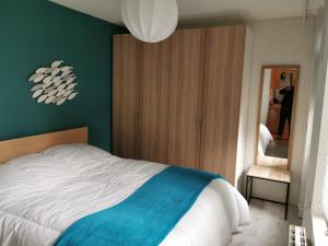 een slaapkamer met een wit bed en een groene muur bij Appartement de charme in Honfleur