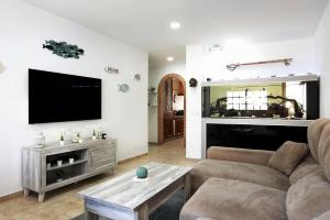 a living room with a couch and a flat screen tv at Villa Acuario - especial familias in Barbate