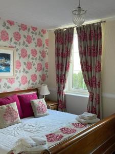 a bedroom with a bed with pink curtains and a window at Portsonachan Hotel & Lodges in Dalmally