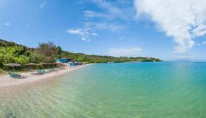 a beach with chairs and umbrellas and the ocean at Siamos Villa in Vonitsa