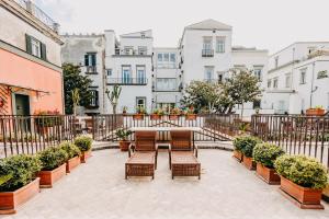 a patio with a table and benches and buildings at Costantinopoli 104 in Naples