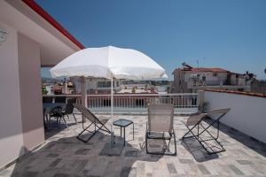 a patio with chairs and a table and an umbrella at Grcka Reni Greece Beach Penthaus 3 in Nea Kalikratia