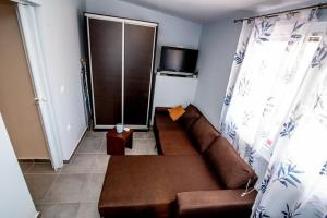 a living room with a brown couch and a television at Grcka Reni Greece Beach Penthaus 3 in Nea Kalikratia