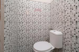 a bathroom with a white toilet and tiled walls at KoolKost Syariah @ Cempaka Putih (Minimum Stay 6 Nights) in Jakarta +33 photos