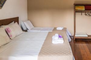 a room with two beds with towels and a couch at Pousada dos Sinos in São João del Rei