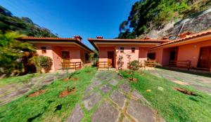 a house with a grassy yard next to a building at Pousada Albuquerque in Teresópolis