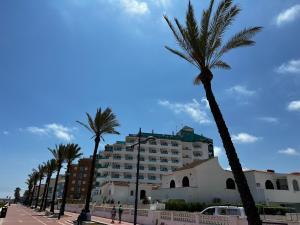 a large building with palm trees in front of it at Hotel Hey Peñíscola in Peñíscola