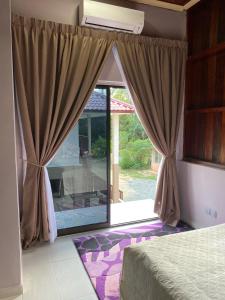 a bedroom with a large glass door to a patio at Teratak Sekayu ( Room Stay ) in Kuala Kerau