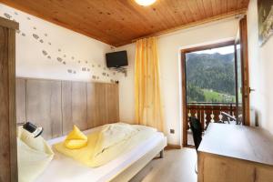 a bedroom with a bed and a large window at Veltierhof in Funes