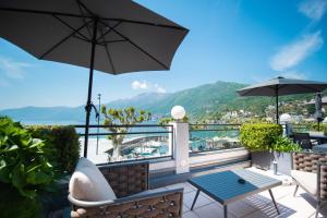 - un balcon avec une table et un parasol dans l'établissement Hotel la Meridiana, Lake & SPA, à Ascona