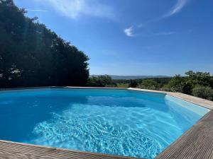 une grande piscine bleue avec une terrasse en bois dans l'établissement Sainte Victoire le Cabanon, à Puyloubier