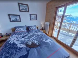 um quarto com uma cama com um edredão azul e uma janela em Appartement Villard-sur-Doron, 3 pièces, 6 personnes - FR-1-293-354 em Villard-sur-Doron