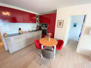 une cuisine avec des placards rouges, une table et des chaises dans l'établissement Appartement Bénodet, 2 pièces, 2 personnes - FR-1-481-110, à Bénodet