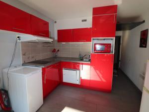 a red kitchen with a white refrigerator and red cabinets at Studio Le Grau-du-Roi, 1 pièce, 4 personnes - FR-1-307-198 in Le Grau-du-Roi