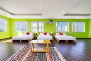 a green room with two beds and a table at Joi Hospitality - Central in Vung Tau